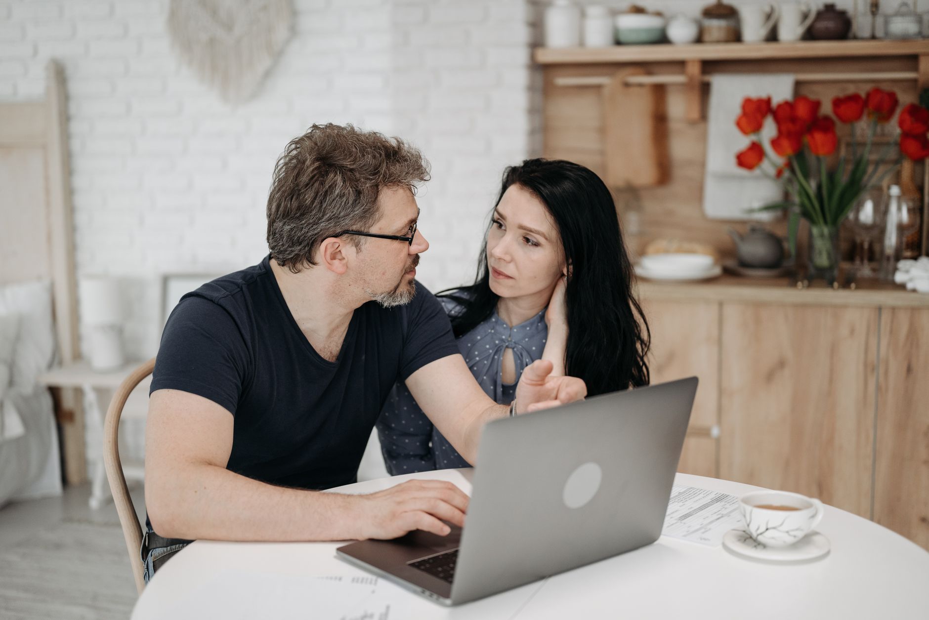A couple at their kitchen table going through plans on a laptop