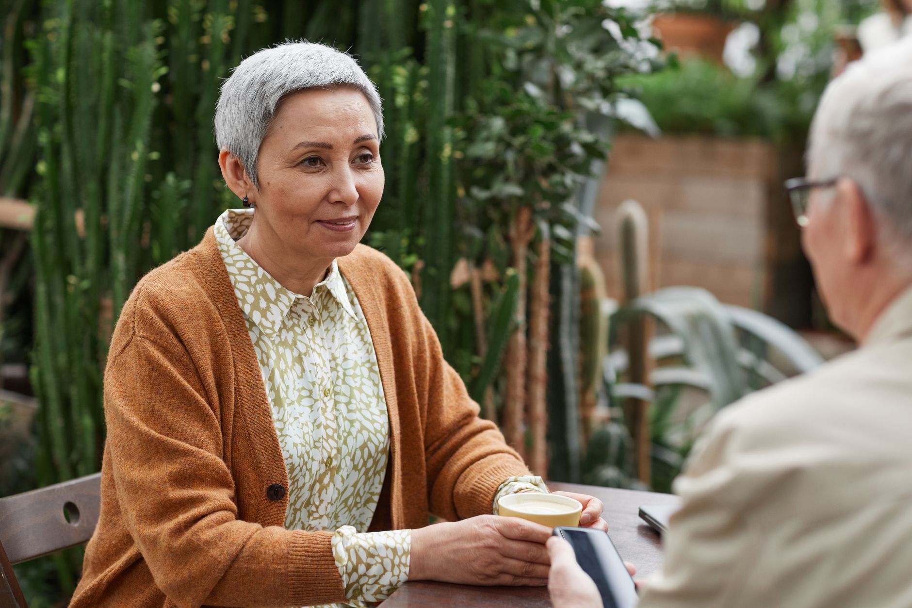 A long-term couple talking over coffee on a porch
