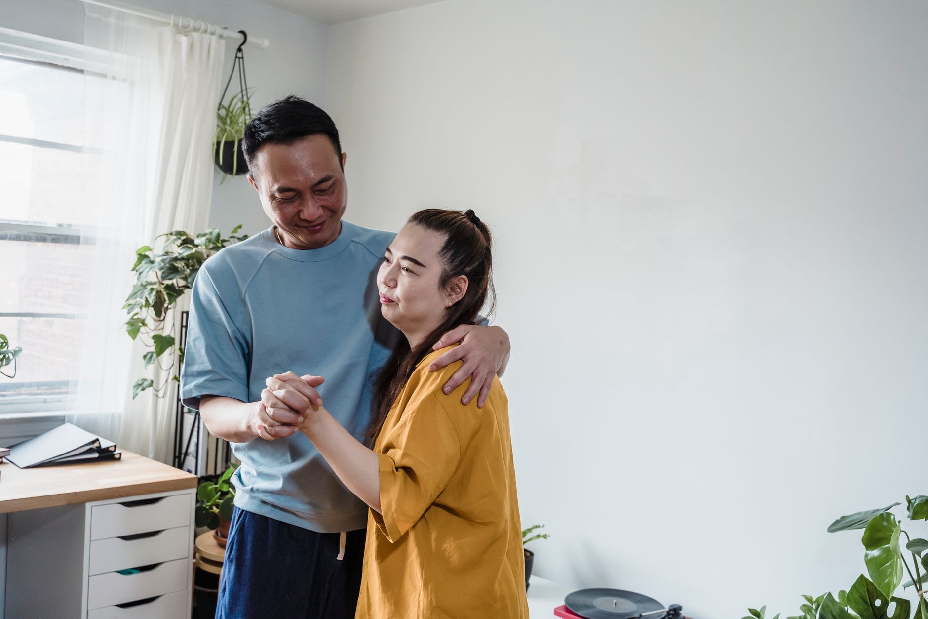 A couple slow dancing in their kitchen in the evening